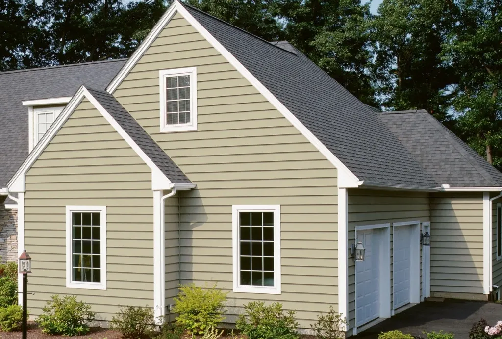 Two-story house with sage green siding, white windows and a gray shingle roof
