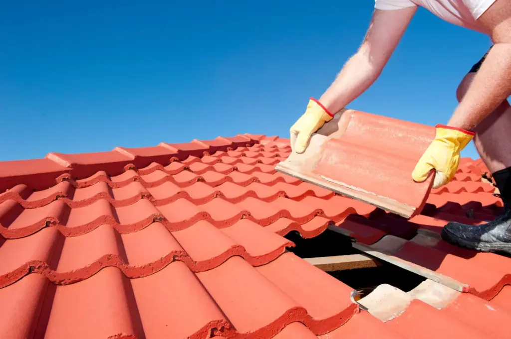 Worker placing red clay roof tiles