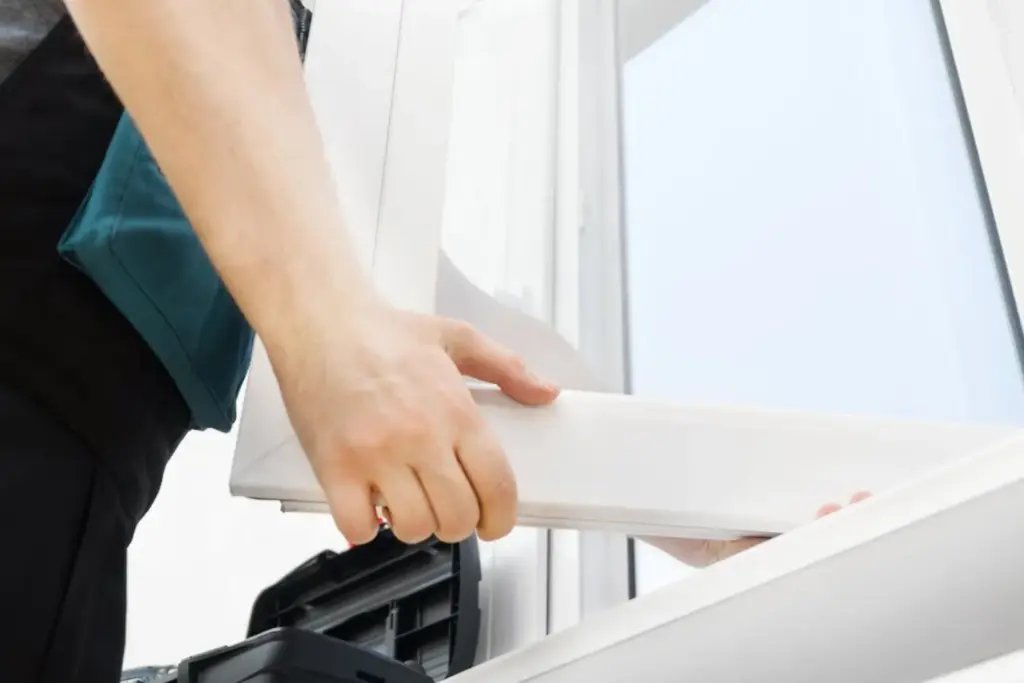 Installer fitting a white vinyl window frame