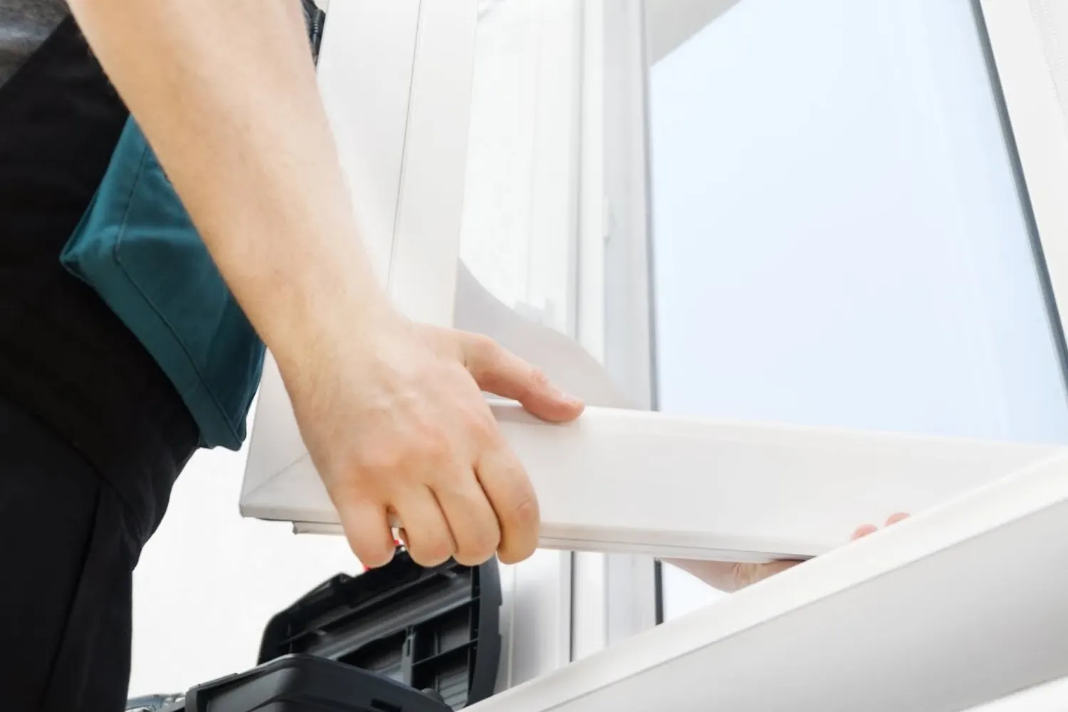 Installer fitting a white vinyl window frame