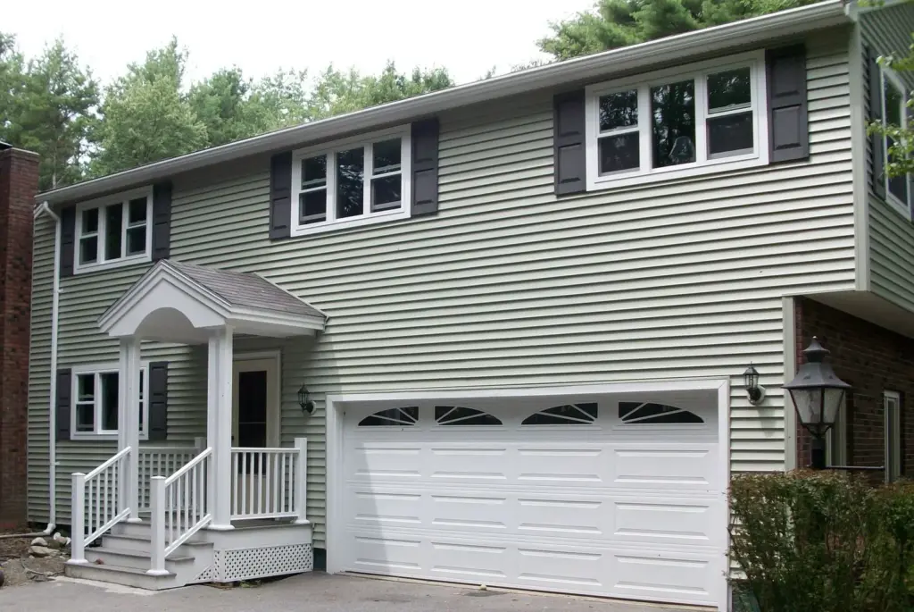 Two-story home with green vinyl siding and a white garage door
