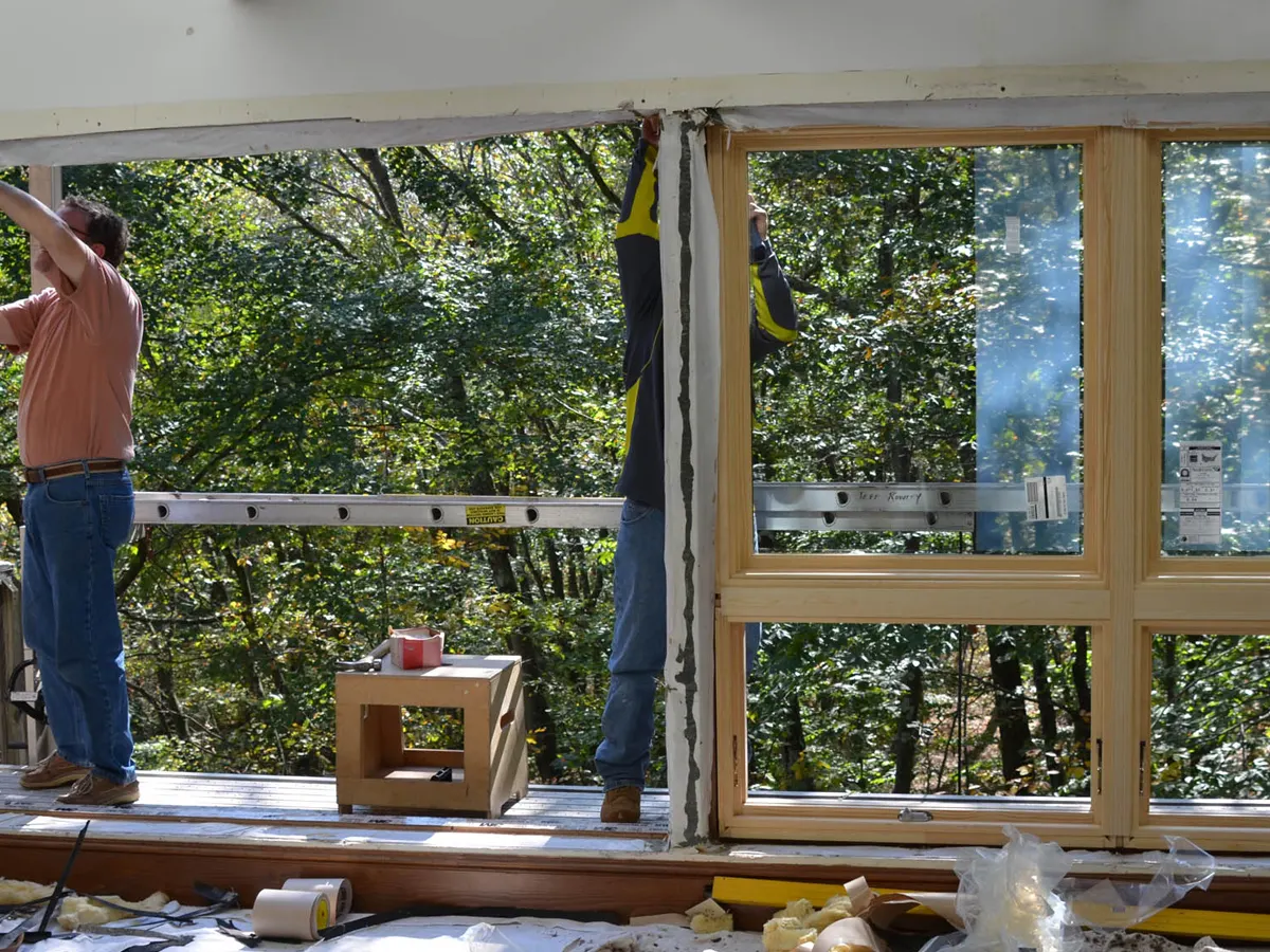 Installers fitting a large new window frame into a wall opening